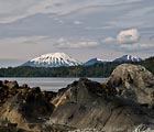 The shoreline rocks accentuate the shape of the mountains across the bay from Sitka.