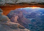 The sun breaks under Mesa Arch at dawn in Canyonlands National Park.