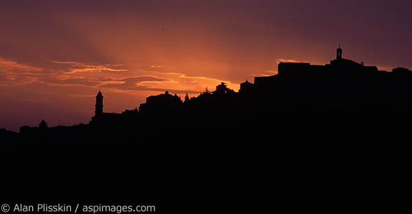Final rays of daylight backlight this hillside Tuscan town.